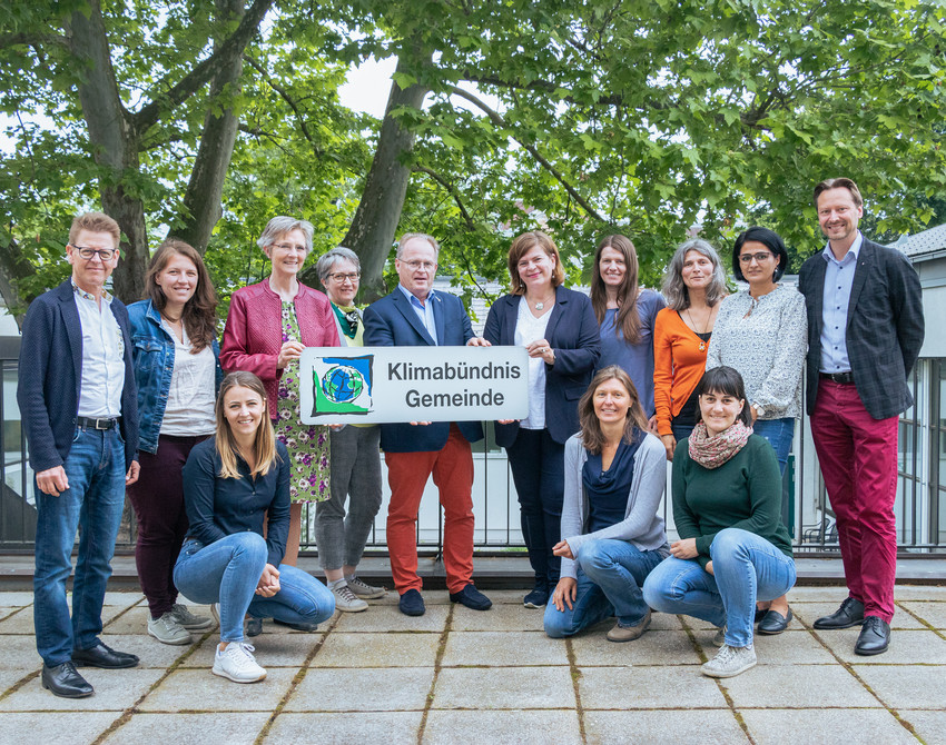 Die Mitarbeiter:innen und das Vorstandsteam stehen für ein Gruppenfoto auf einer Terasse.
