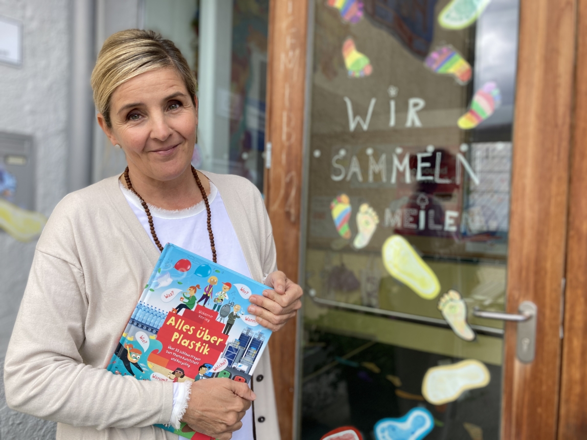 Lehrerin der Volksschule Telfes mit Buch vor dem Eingang der Schule