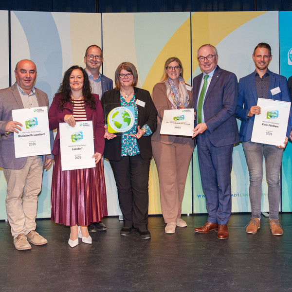 Gemeindevertreter:innen stehen auf der Bühne und halten einen Klima-Kalender in der Hand.