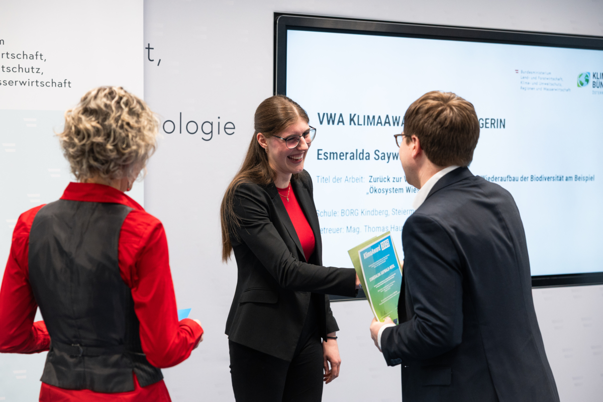 Übergabe des VWA Klima Awards Mädchen nimmt lachend Urkunde von Simon Ellmauer-Klambauer entgegen