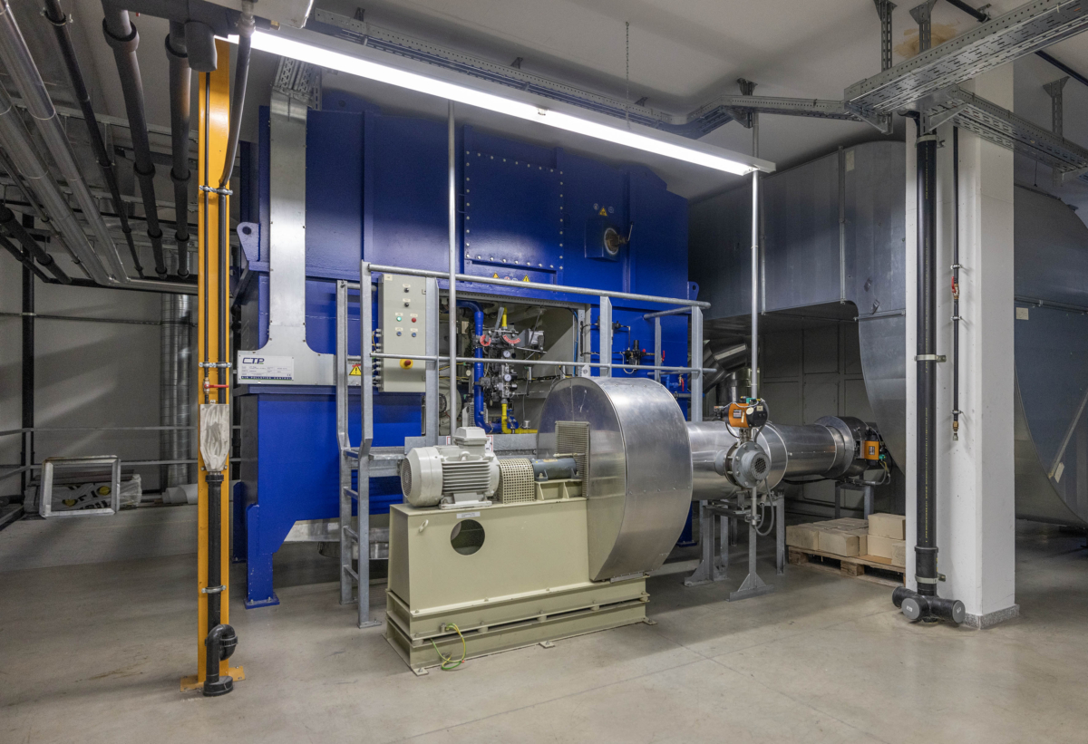 Technischer Raum mit großer Industrieanlage, Rohren und Maschinen.