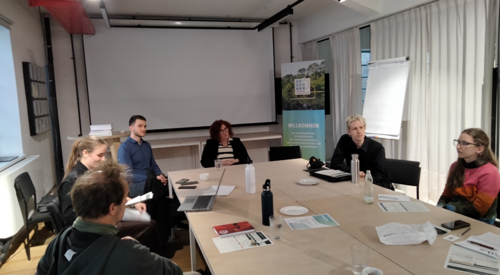 Mehrere Erwachsene sitzen um einen Tisch und diskutieren