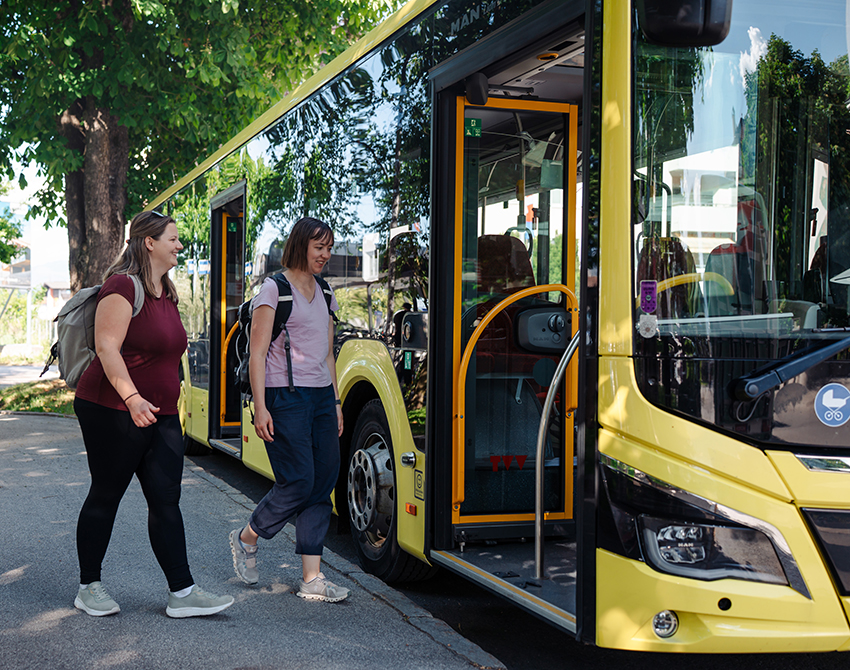 zwei junge Frauen steigen in einen Bus ein.